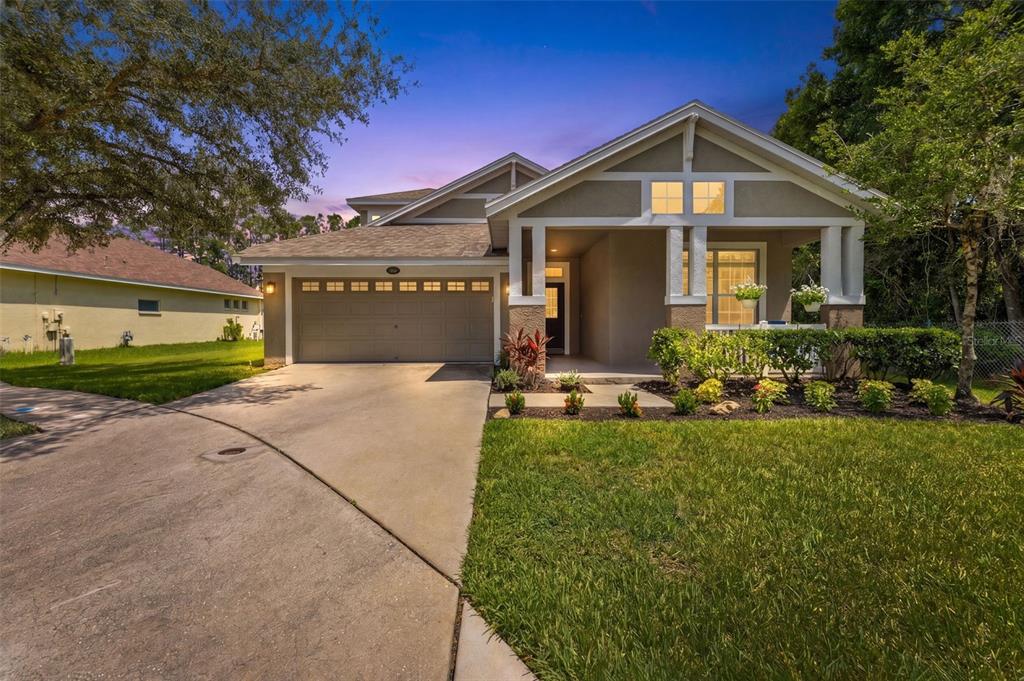 A single-story house with a two-car garage, a covered front porch, and a concrete driveway — 5154 PHEASANT WOODS DRIVE, LUTZ, FL