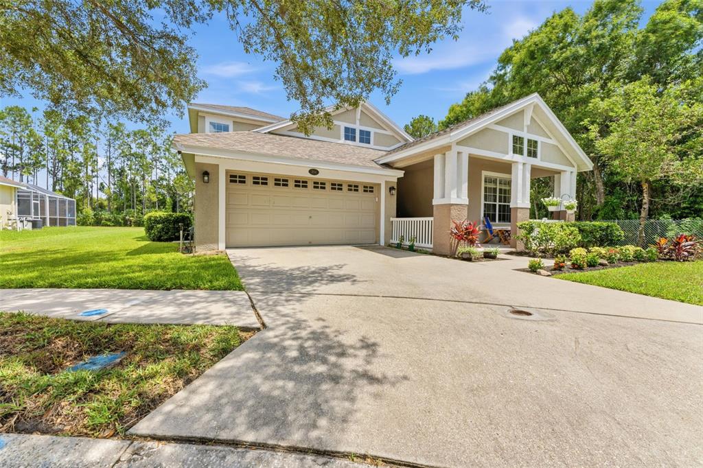 A tan suburban house with a two-car garage, front porch, and surrounding green lawn — 5154 PHEASANT WOODS DRIVE, LUTZ, FL