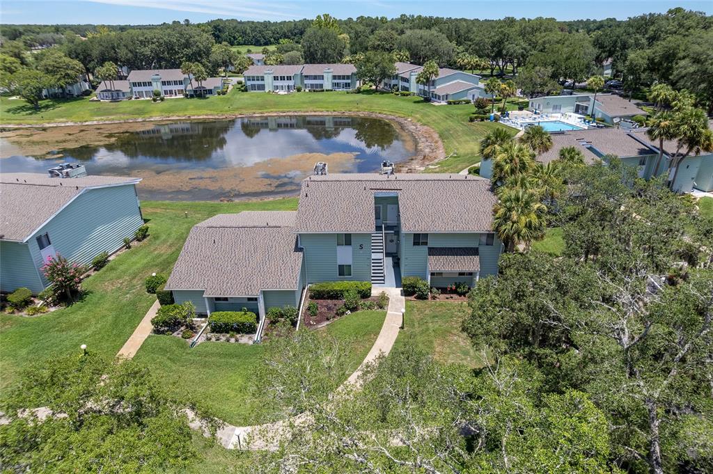 An aerial view shows a multi-story apartment building with a pond and swimming pool nearby — 545 MIDWAY DRIVE UNIT A, OCALA, FL