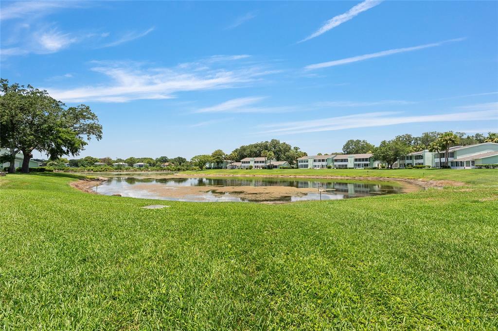 A grassy lawn leads to a pond with apartment buildings in the background — 545 MIDWAY DRIVE UNIT A, OCALA, FL