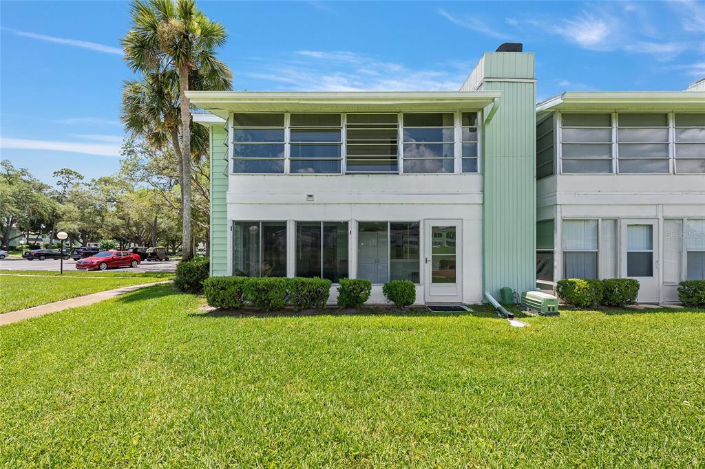 The exterior of a two-story residential building features a ground-level enclosed patio and green siding — 545 MIDWAY DRIVE UNIT A, OCALA, FL