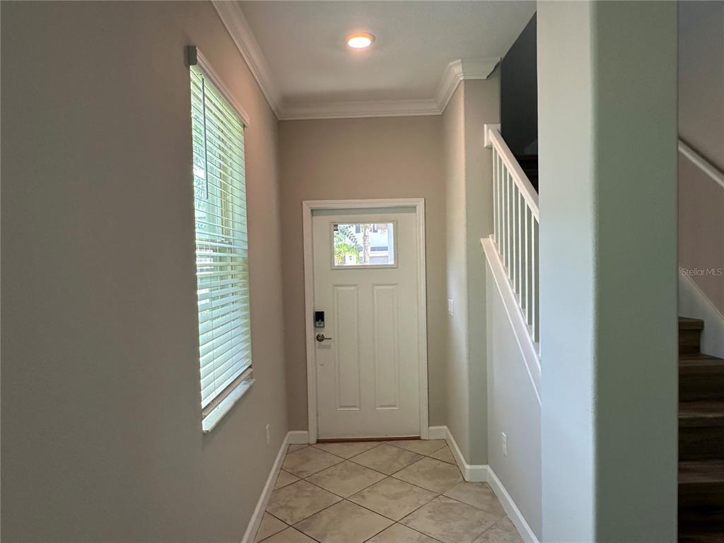 An entryway features tile flooring, a white front door, a window with blinds, and stairs — 1389 WHITE FOX RUN, LUTZ, FL