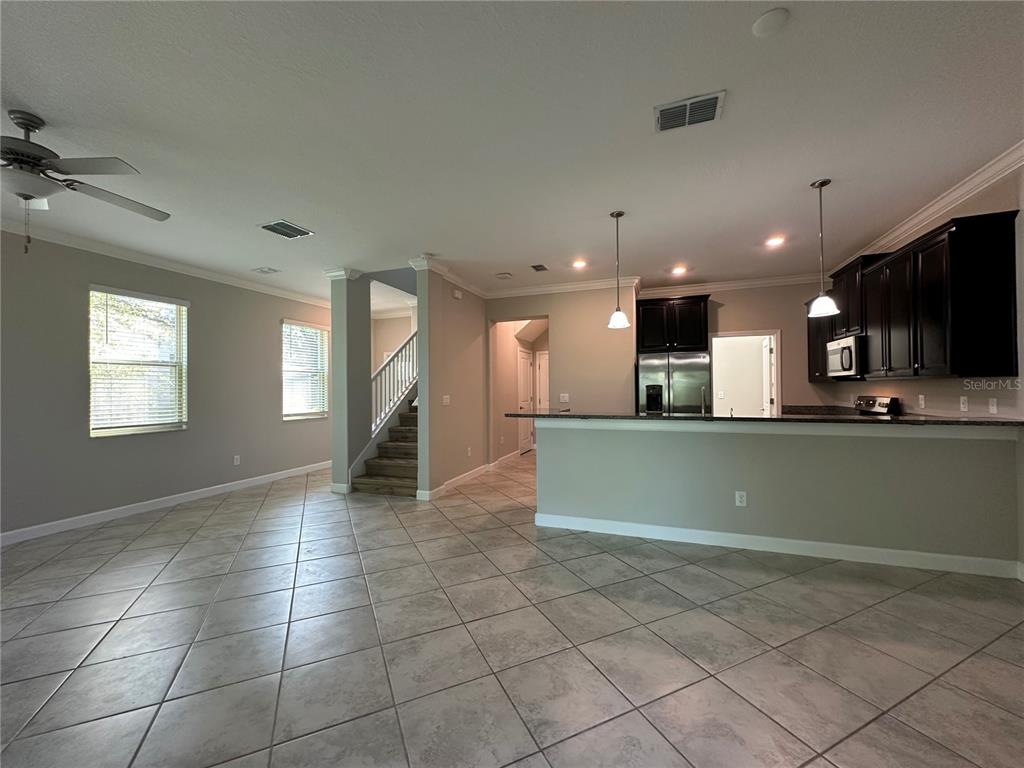 An open-concept kitchen and living area features tile flooring, dark cabinetry, and a staircase — 1389 WHITE FOX RUN, LUTZ, FL
