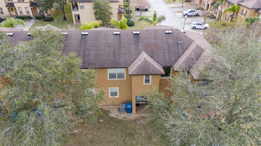 An aerial view of a multi-story tan townhouse with a brown shingled roof — 3132 CALABRIA AVENUE, DAVENPORT, FL