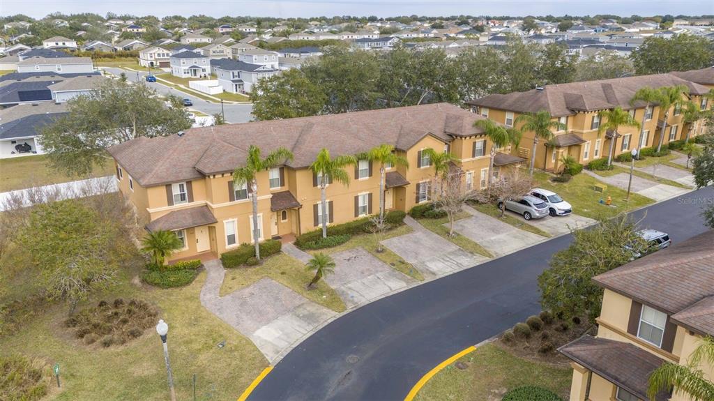 An aerial view shows a multi-unit tan townhouse building with a brown roof and driveways — 3132 CALABRIA AVENUE, DAVENPORT, FL