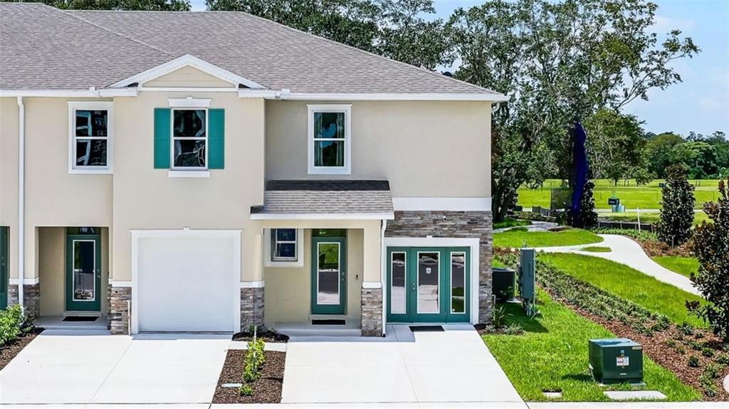 An exterior view of a two-story townhouse with a garage, stone accents, and green shutters — 14385 CANVAS STREET, ORLANDO, FL