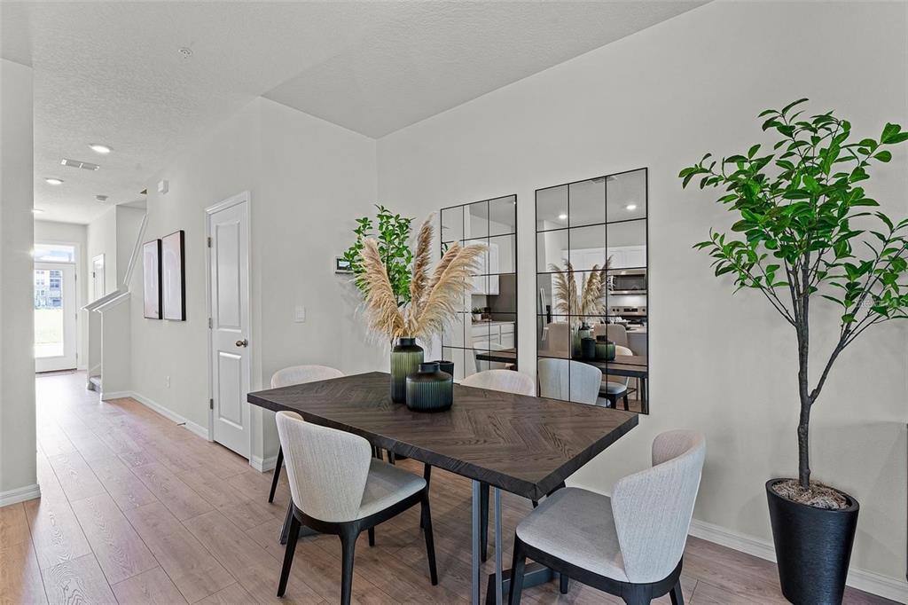 A dining area features a dark wood table, light chairs, wall mirrors, and a potted plant — 14385 CANVAS STREET, ORLANDO, FL