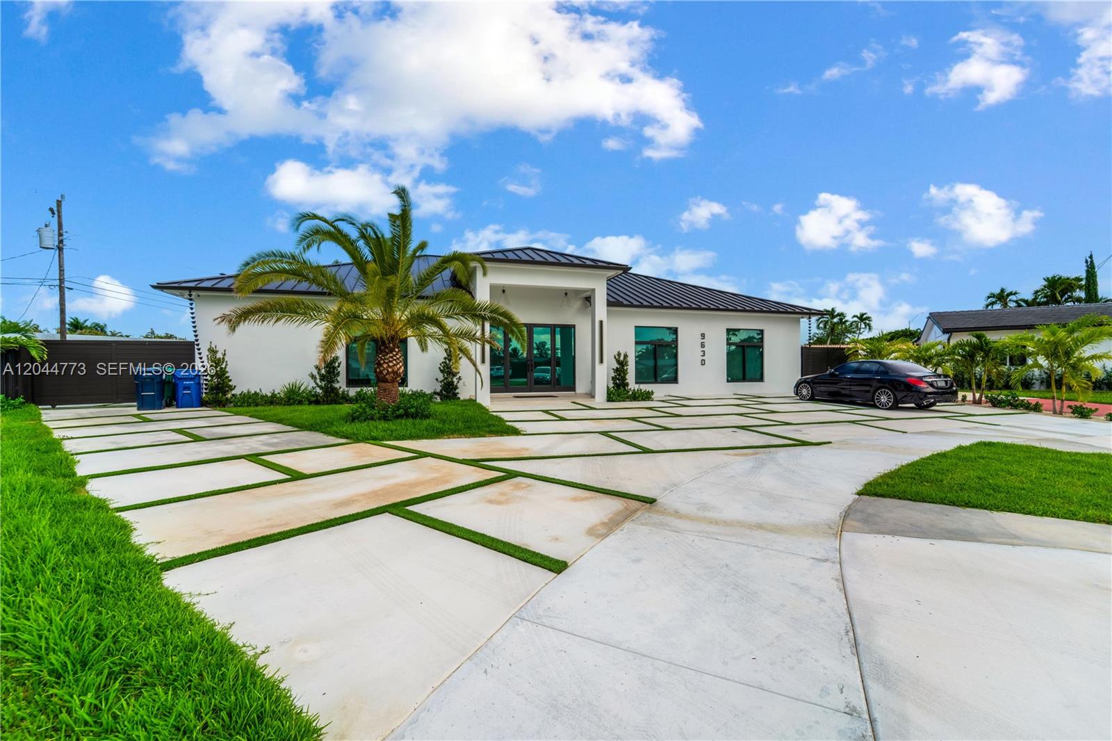 A modern single-story house features a large palm tree and a geometric concrete driveway — 9630 SW 10th Ter, Miami FL 33174, MIAMI, FL