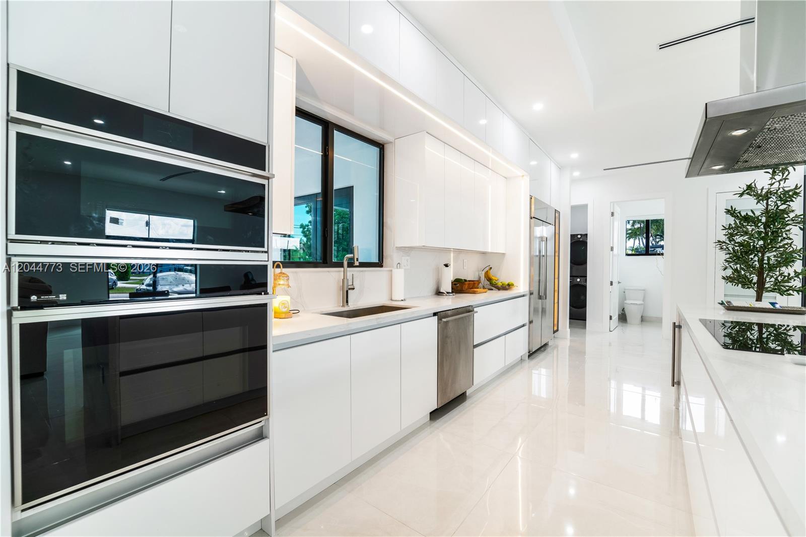 A modern white kitchen features sleek cabinetry, stainless steel appliances, and polished tile flooring — 9630 SW 10th Ter, Miami FL 33174, MIAMI, FL