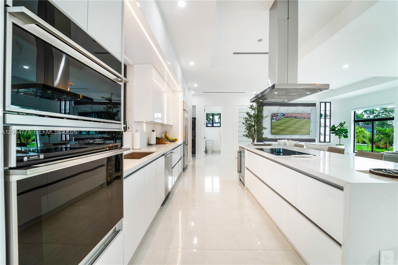 A modern white kitchen features a large island, stainless steel appliances, and glossy cabinetry — 9630 SW 10th Ter, Miami FL 33174, MIAMI, FL