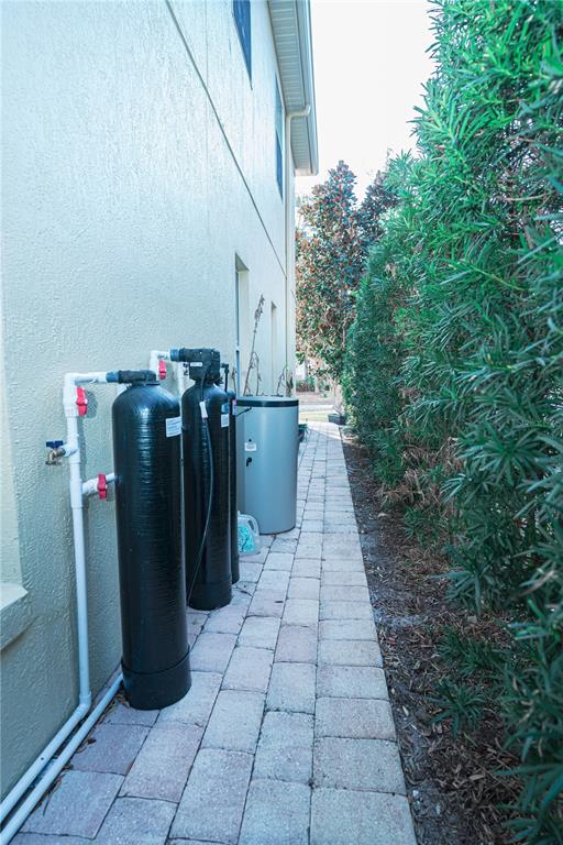 Exterior view of a house side yard featuring water filtration tanks and a paved walkway — 7035 BRESCIA WAY, ORLANDO, FL