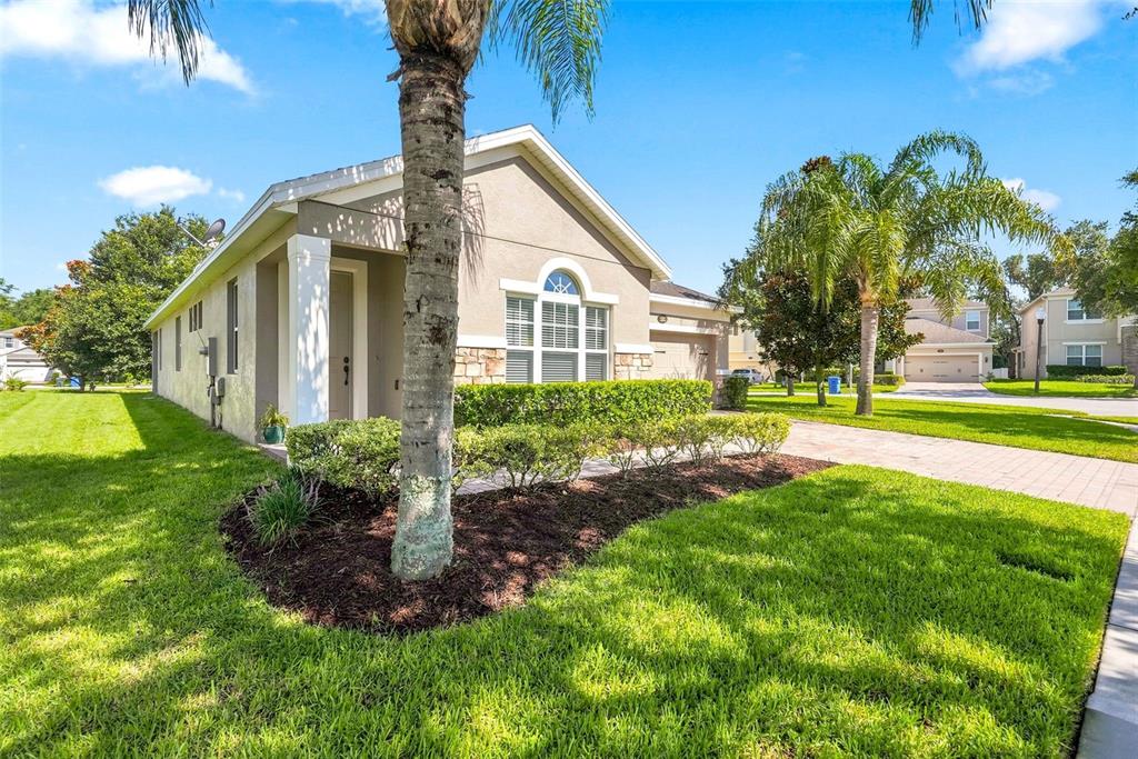 A single-story house with a tan stucco exterior, a paved driveway, and a palm tree — 1061 COSMOS WAY, OVIEDO, FL
