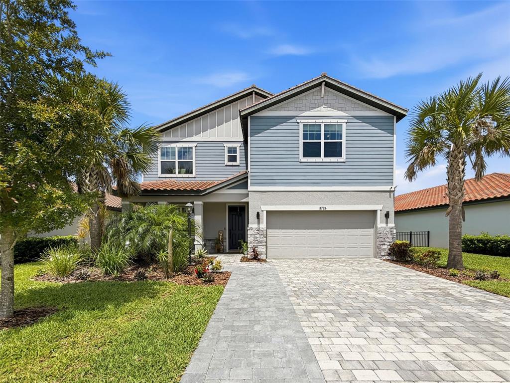 A two-story house with blue siding, a stone-accented garage, and a paved driveway — 3726 SAVANNA PALMS COURT, BRADENTON, FL