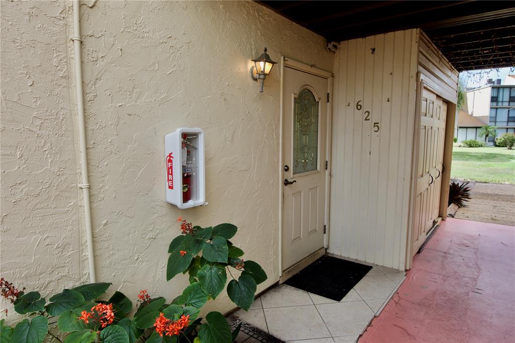 An exterior view of a residential entryway with a fire extinguisher mounted on the wall — 625 WHITE PINE TREE ROAD UNIT 23, VENICE, FL