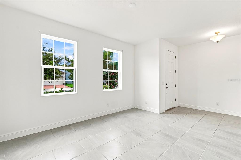 A bright room with white walls, light tile flooring, two windows, and a white door — 5059 TIBET COURT, ST CLOUD, FL