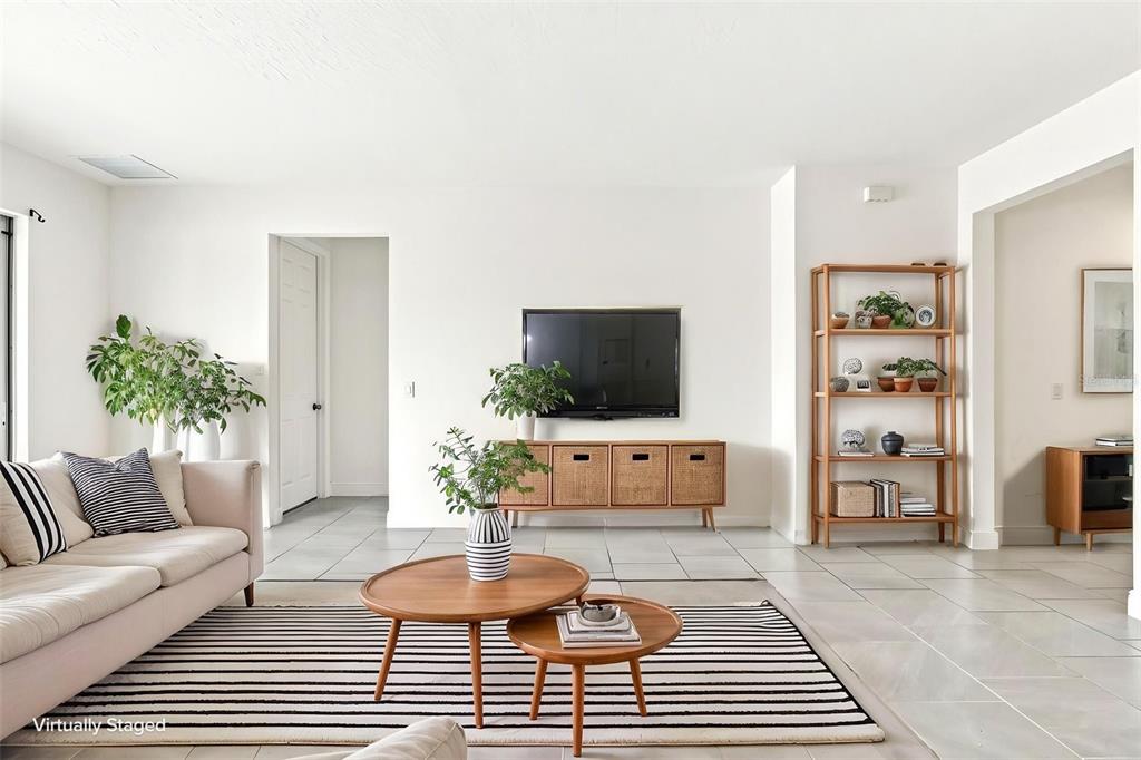 A living room features a beige sofa, nested wooden coffee tables, and a wall-mounted television — 5059 TIBET COURT, ST CLOUD, FL