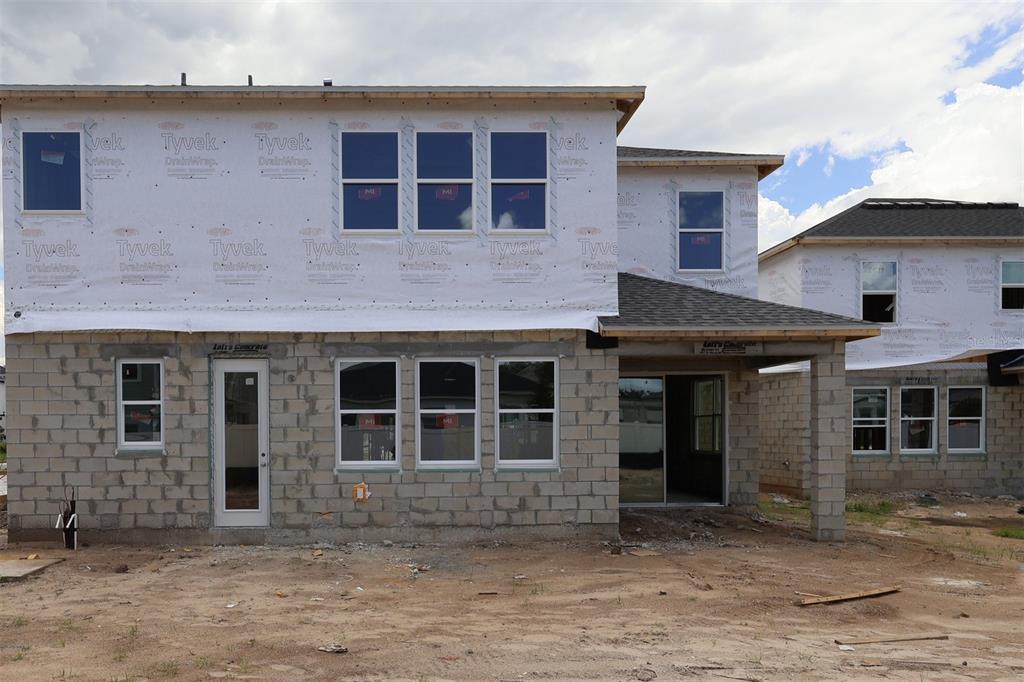 The rear exterior of a two-story house under construction features concrete blocks and Tyvek wrap — 833 RIVER STONE TRAIL, SANFORD, FL