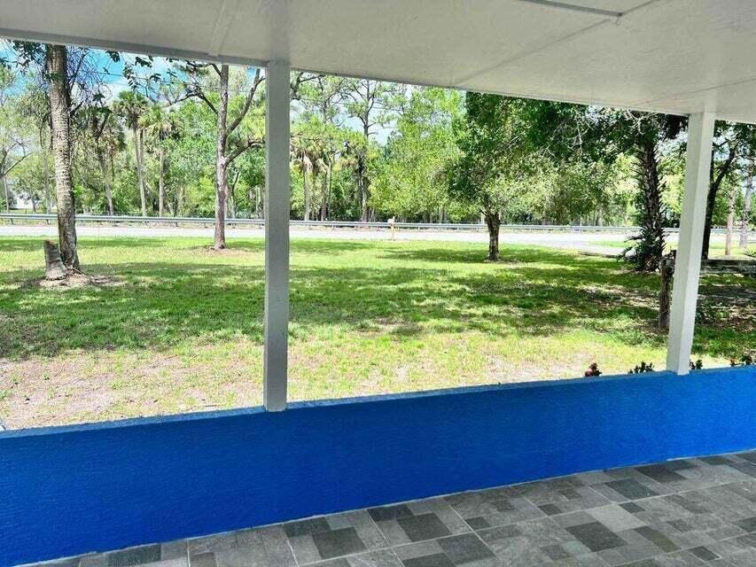 A view from a covered porch looking out onto a grassy yard and trees — 2410 S Brocksmith Road, Fort Pierce FL 34945, FORT PIERCE, FL