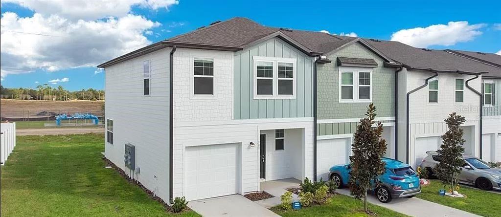 An exterior view of a multi-story townhouse with white siding, a garage, and a driveway — 509 MADISON DRIVE, DAVENPORT, FL