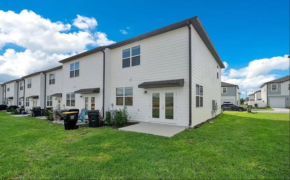 The exterior rear view of a white multi-family townhouse with a small concrete patio — 509 MADISON DRIVE, DAVENPORT, FL