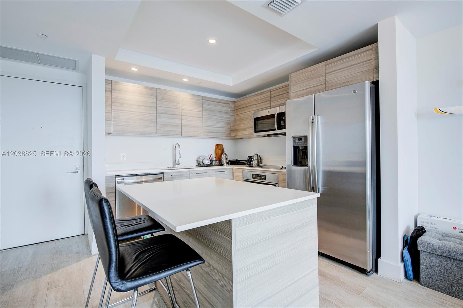 A modern kitchen features light wood cabinetry, stainless steel appliances, and a white island — 121 NE 34th St # 1111, Miami FL 33137, MIAMI, FL