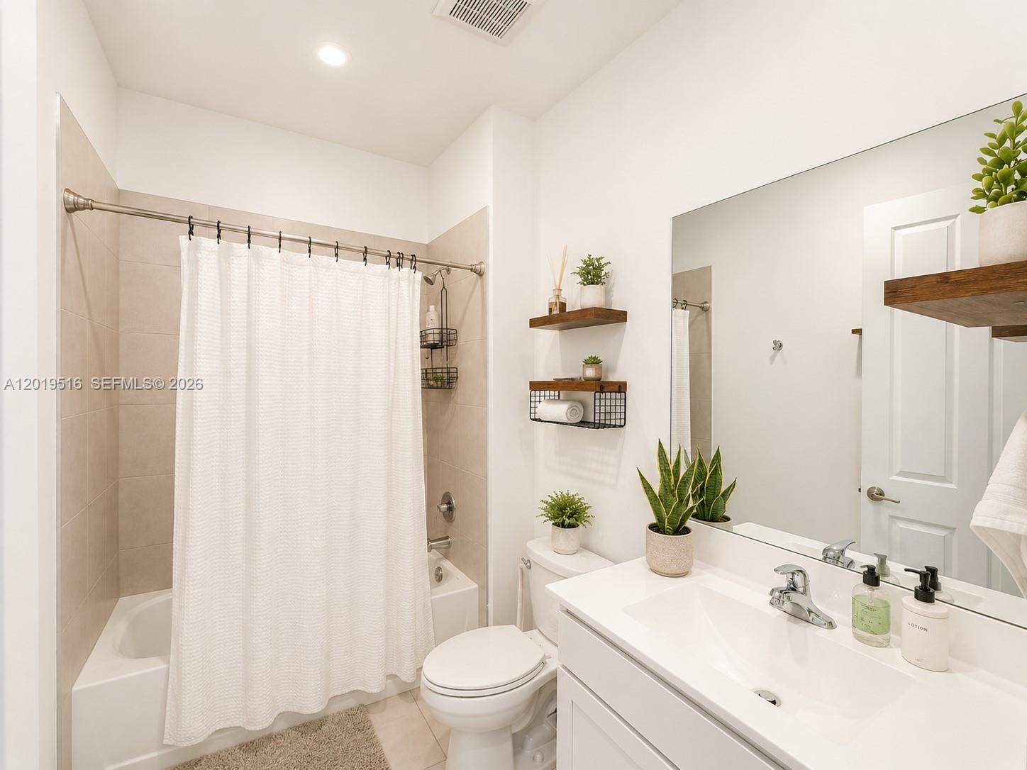 A bathroom features a white vanity, a toilet, and a shower-tub combination with beige tiles — 1248 Wandering Willow Way # 1248, Loxahatchee FL 33470, LOXAHATCHEE, FL