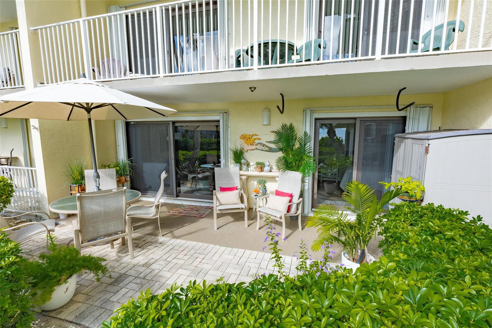 A ground-floor patio features a dining set, two chairs, and a white umbrella — 4450 Highway A1a # 102, Vero Beach FL 32963, VERO BEACH, FL
