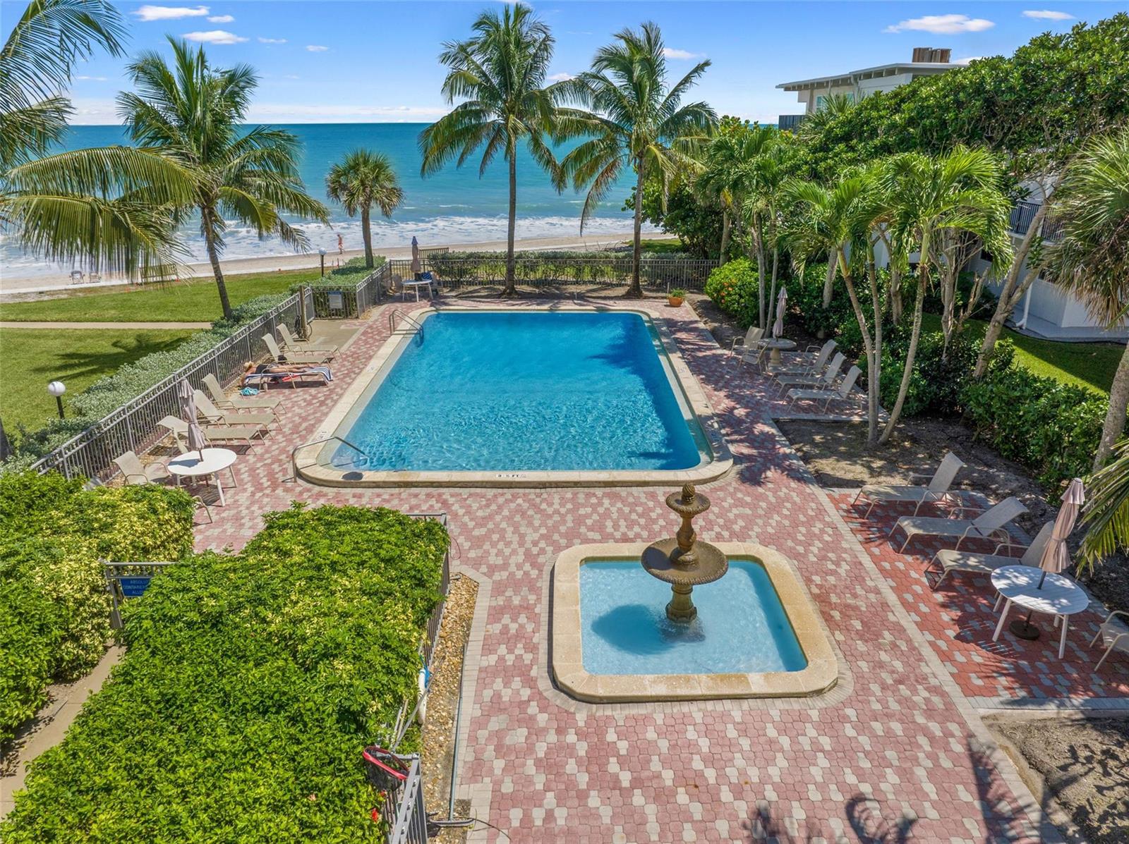 An aerial view of a swimming pool and fountain on a brick patio by the ocean — 4450 Highway A1a # 102, Vero Beach FL 32963, VERO BEACH, FL
