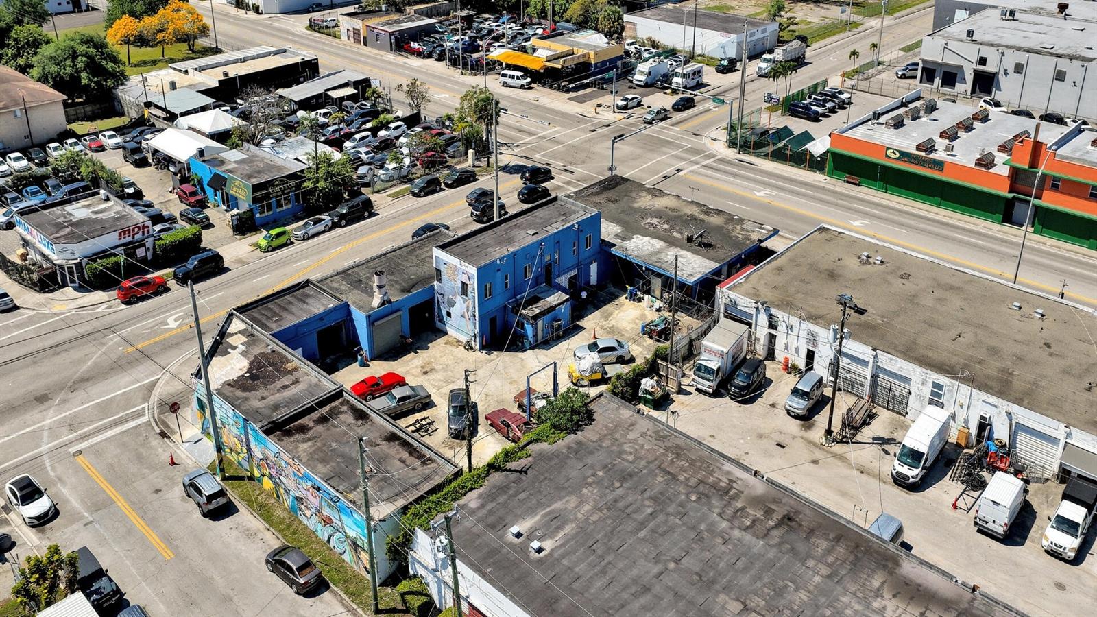 An aerial view shows a commercial property with a blue building and surrounding parking lots — 7101 NW 7th Avenue, Miami FL 33150, MIAMI, FL