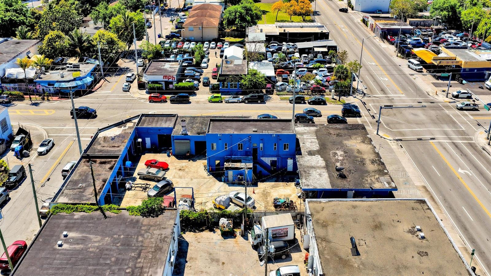 An aerial view shows a blue commercial building with a central parking lot and surrounding streets — 7101 NW 7th Avenue, Miami FL 33150, MIAMI, FL