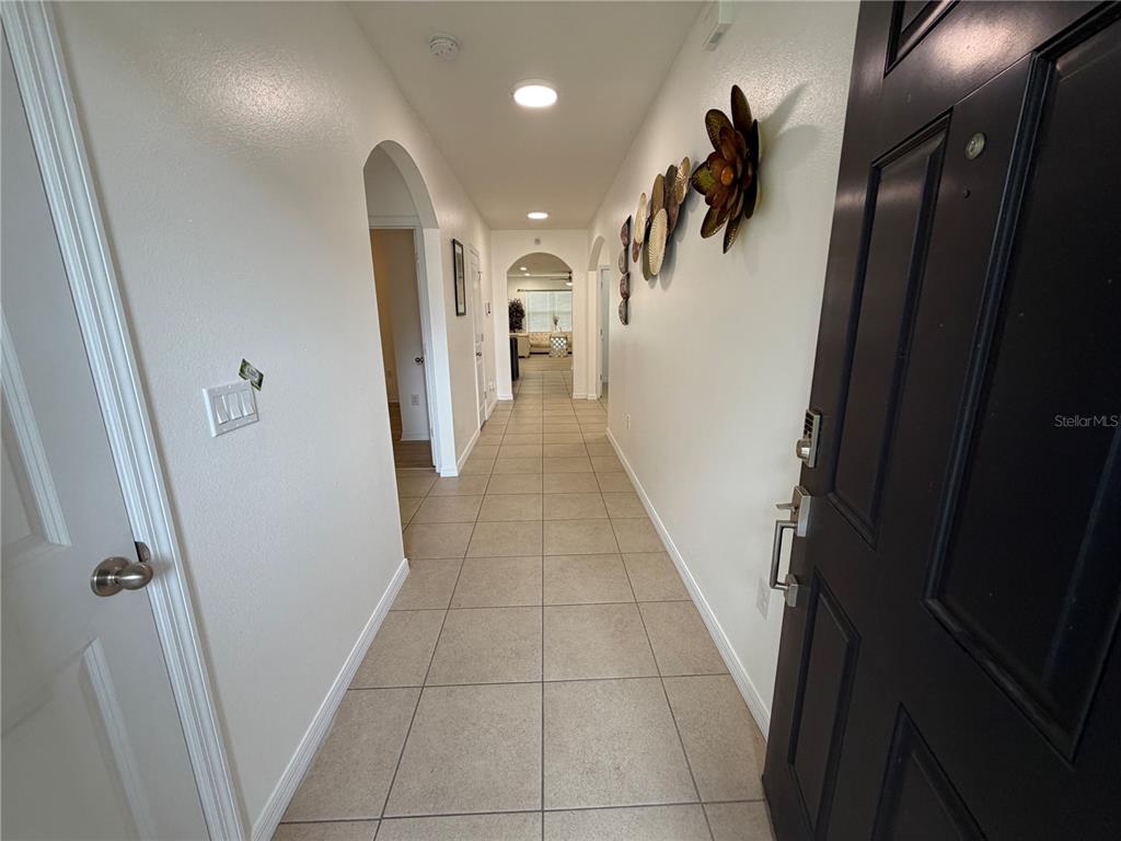 A tiled hallway leads from a black front door toward an arched entryway — 8106 BILSTON VILLAGE LANE, GIBSONTON, FL