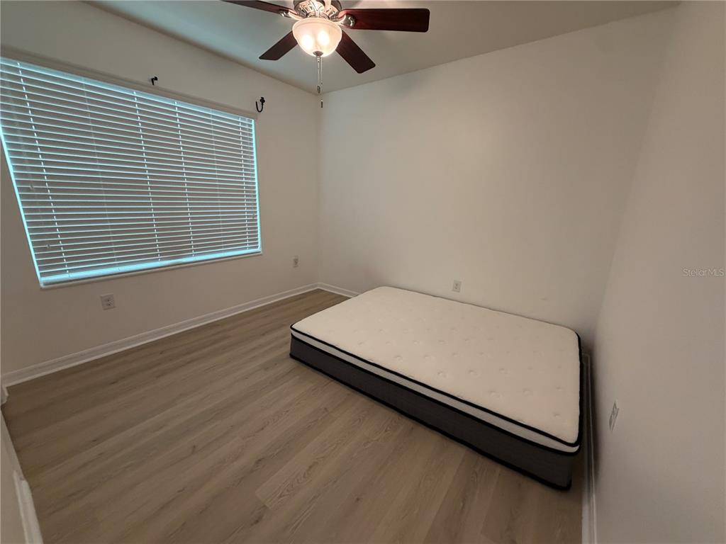 An empty bedroom features light wood-look flooring, white walls, and a ceiling fan — 8106 BILSTON VILLAGE LANE, GIBSONTON, FL
