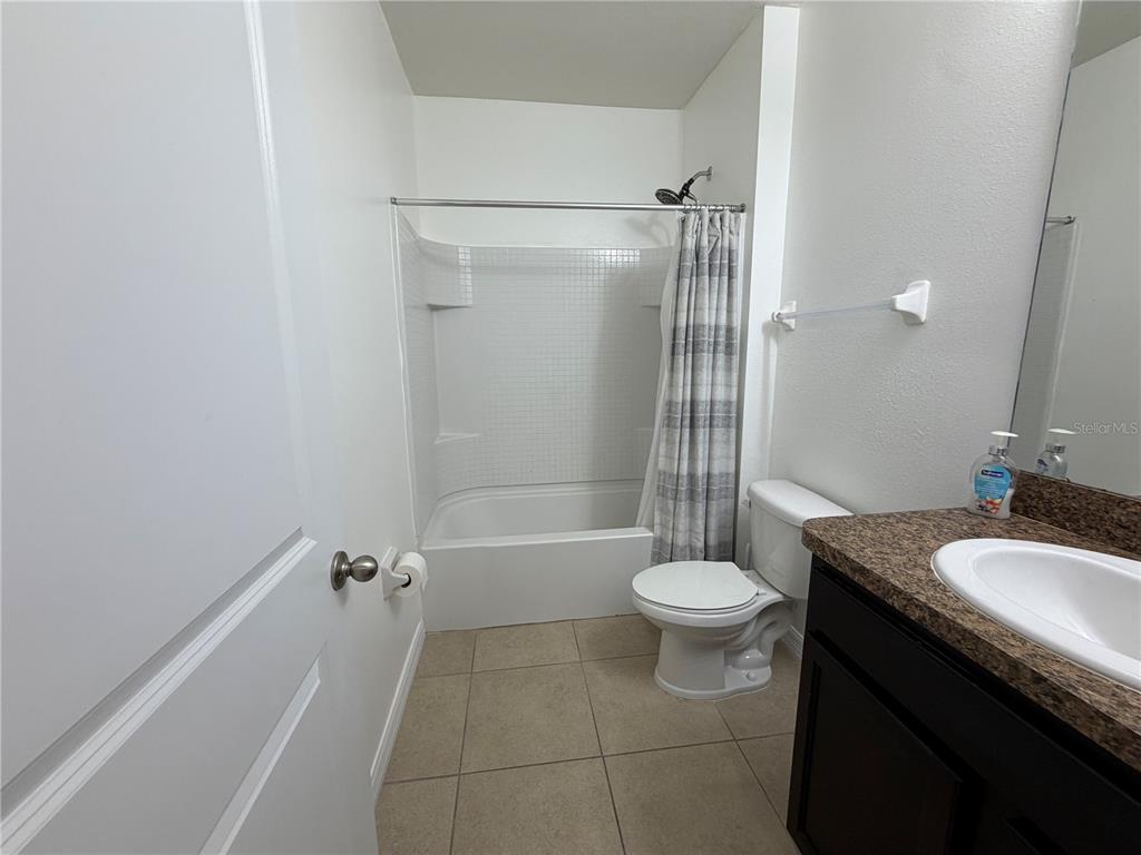 A bathroom features a tiled tub-shower combination, a white toilet, and a dark wood vanity — 8106 BILSTON VILLAGE LANE, GIBSONTON, FL