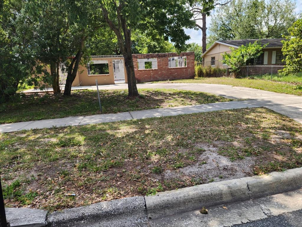 A partially demolished house with exposed brick walls and a concrete driveway sits behind trees — 2260 WILLIE MAYS PARKWAY, ORLANDO, FL