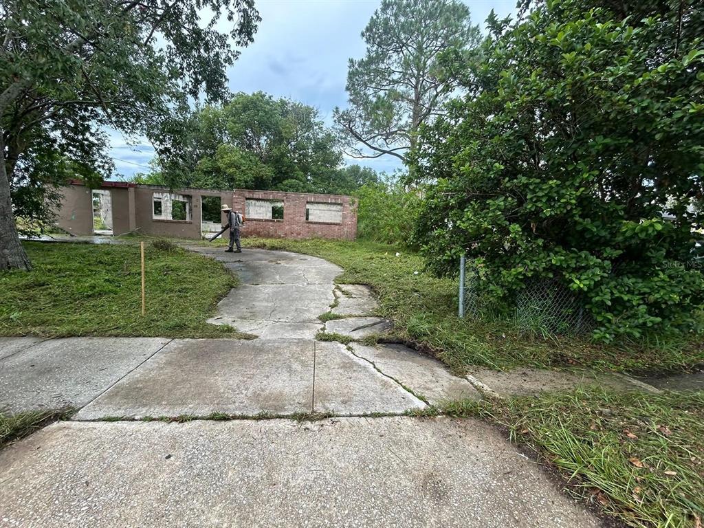 A person uses a leaf blower on the driveway of a dilapidated, roofless brick house — 2260 WILLIE MAYS PARKWAY, ORLANDO, FL