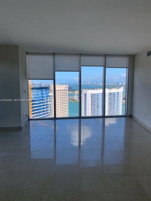 An empty room with light-colored tile floors and floor-to-ceiling windows overlooking a city skyline — 465 Brickell Ave # 4902, Miami FL 33131, MIAMI, FL