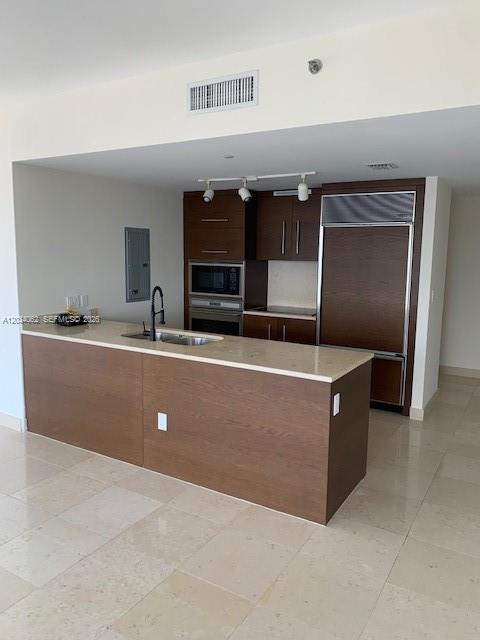 A modern kitchen features a large island, dark wood cabinetry, and light-colored stone countertops — 465 Brickell Ave # 4902, Miami FL 33131, MIAMI, FL