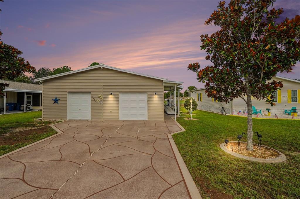 A beige house with a two-car garage and a patterned concrete driveway at sunset — 14269 RIALTO AVENUE, BROOKSVILLE, FL