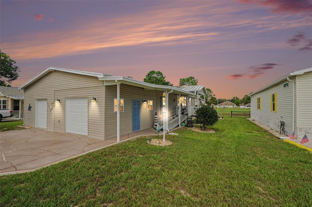 A beige house with a two-car garage and a covered porch under a sunset sky — 14269 RIALTO AVENUE, BROOKSVILLE, FL