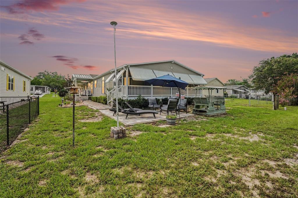The exterior of a manufactured home features a patio, a blue umbrella, and a lawn — 14269 RIALTO AVENUE, BROOKSVILLE, FL