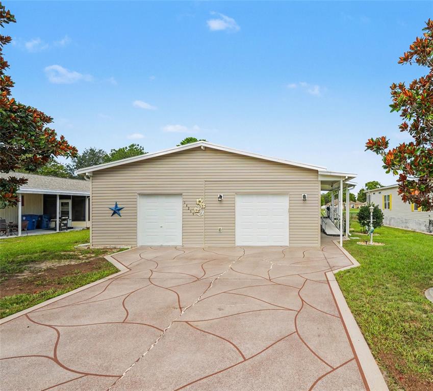 A beige house with two garage doors and a decorative patterned concrete driveway — 14269 RIALTO AVENUE, BROOKSVILLE, FL