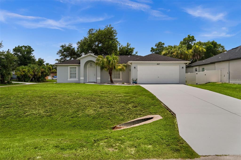 A single-story house with a white garage, arched entryway, and a sloped front lawn — 2217 PICKARD LANE, NORTH PORT, FL