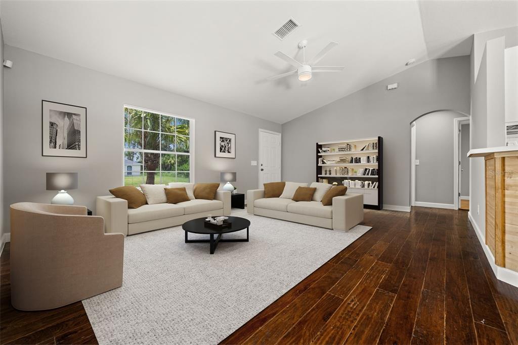 A living room features light gray walls, dark hardwood floors, two sofas, and a ceiling fan — 2217 PICKARD LANE, NORTH PORT, FL