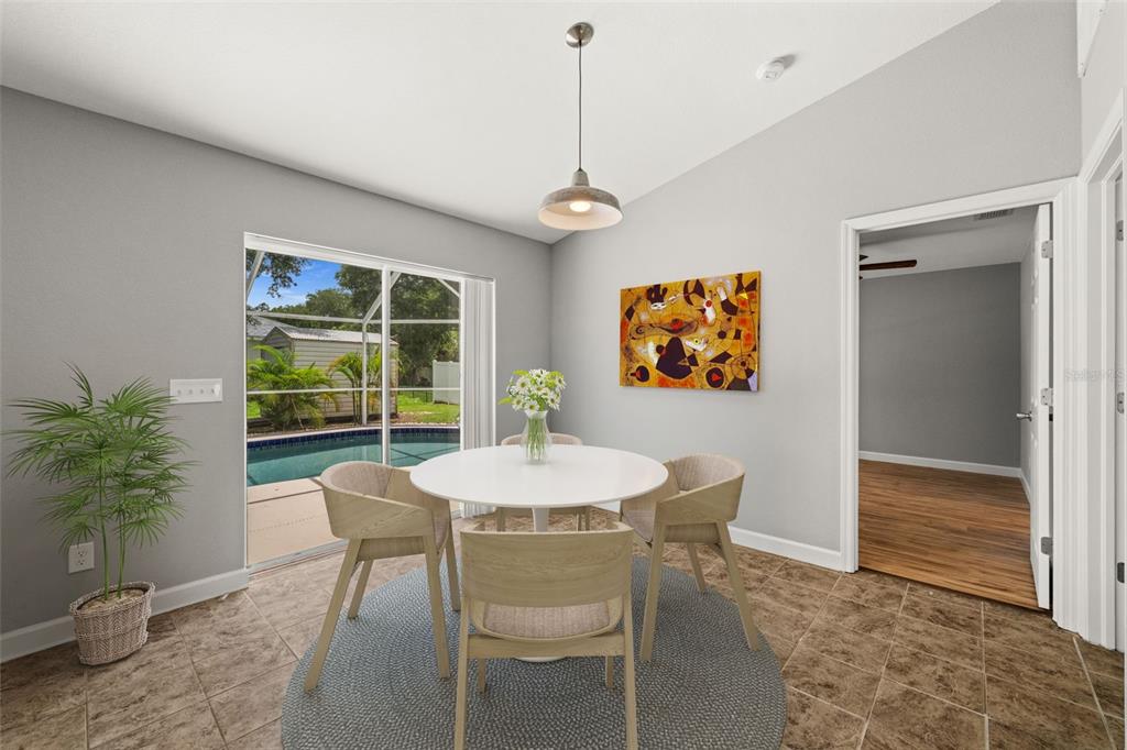 A dining area with a round table, four chairs, and a sliding door to a pool — 2217 PICKARD LANE, NORTH PORT, FL