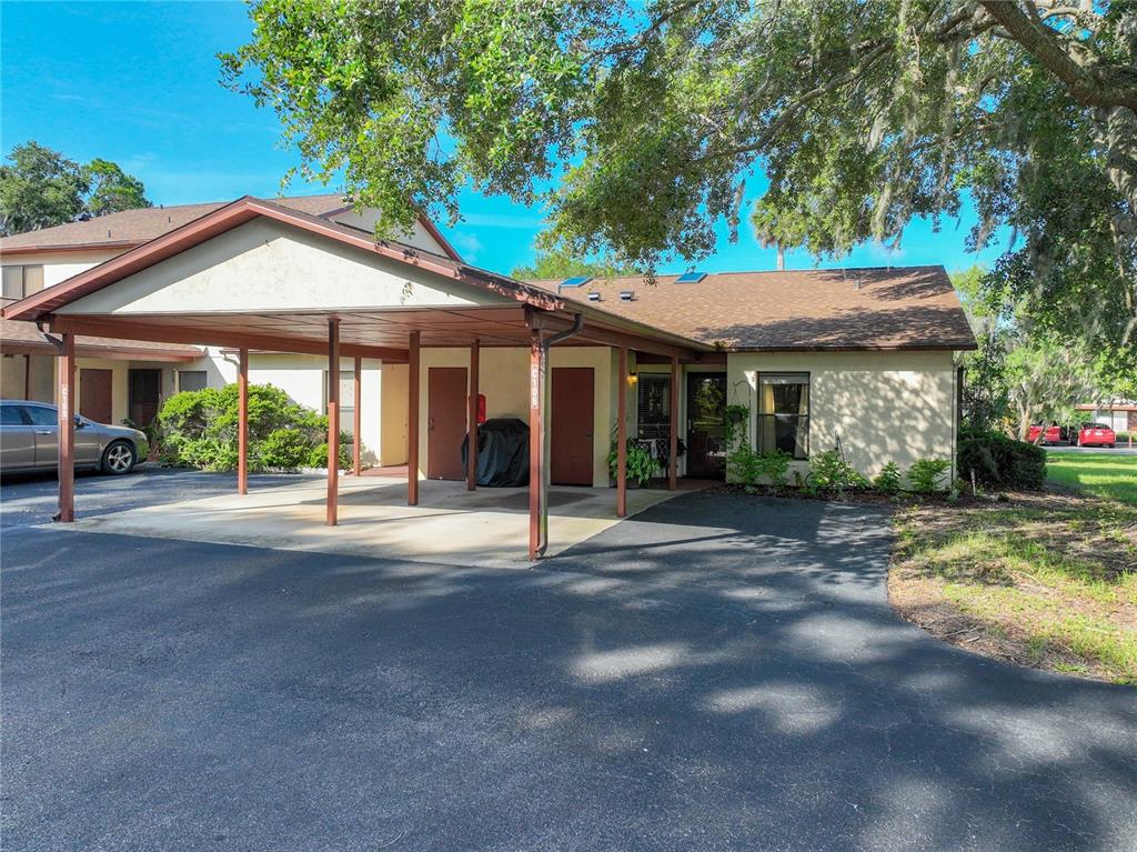A single-story residential building features a covered carport and a paved driveway — 4300 BAYWOOD BOULEVARD UNIT C106, MOUNT DORA, FL
