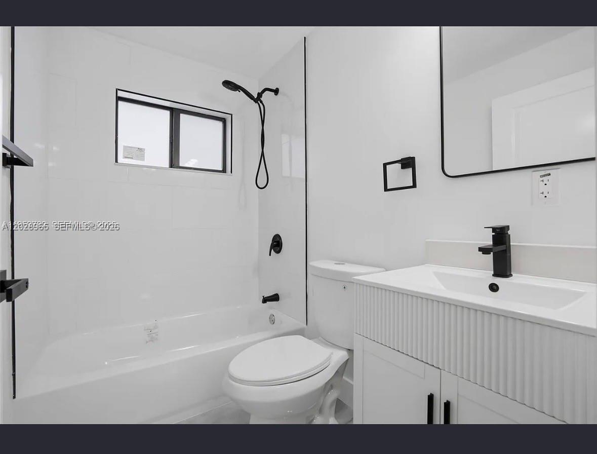 A modern bathroom features a white vanity, a toilet, and a shower-tub combination with black fixtures — 1411 NW 40th St # 1, Miami FL 33142, MIAMI, FL