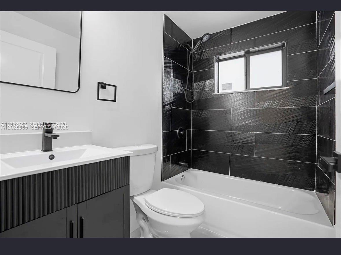 A bathroom features a black vanity, white sink, toilet, and a tub with black tile — 1411 NW 40th St # 1, Miami FL 33142, MIAMI, FL