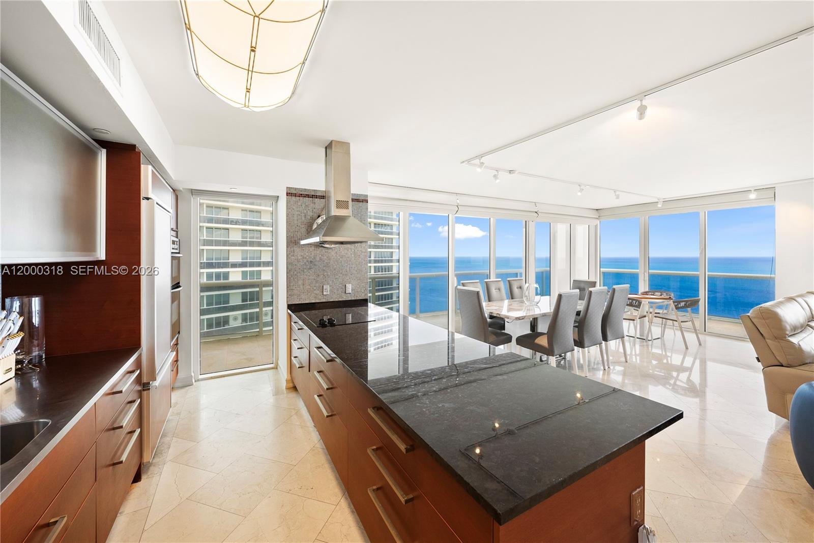 A modern kitchen with dark wood cabinets and black countertops overlooks the ocean — 1850 S Ocean Dr # 3301, Hallandale Beach FL 33009, HALLANDALE BEACH, FL