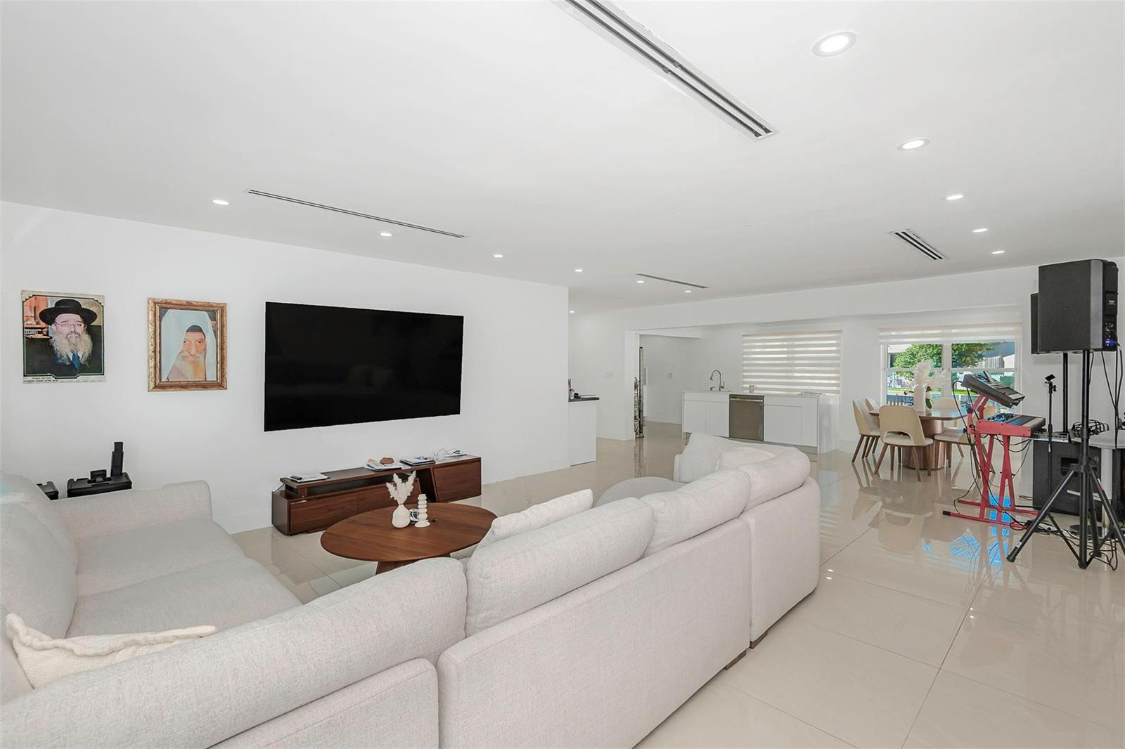 A bright, open-concept living room features a large sectional sofa, television, and dining area — 825 Argonaut Isle, Dania Beach FL 33004, DANIA BEACH, FL