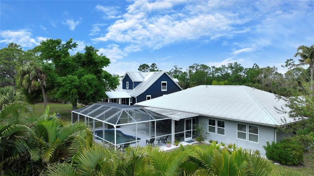 An exterior view of a house with a metal roof and a screened-in swimming pool — 25101 KIMBERLY COURT, PUNTA GORDA, FL